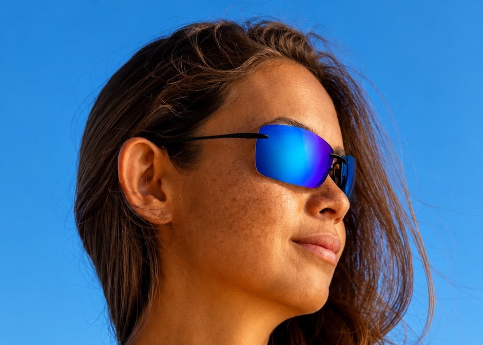 Femme portant des lunettes de soleil aux verres miroités bleus sur fond de ciel bleu